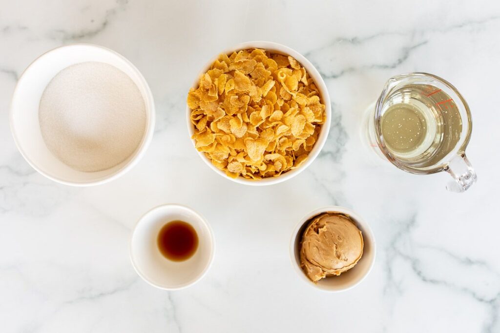 A marble surface with small bowls full of ingredients for cornflake cookies.