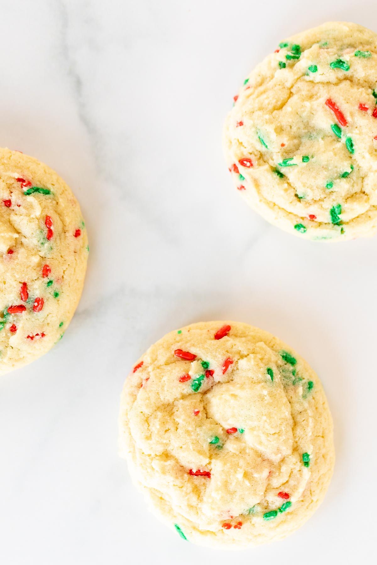Homemade Christmas funfetti cookies on a white surface.