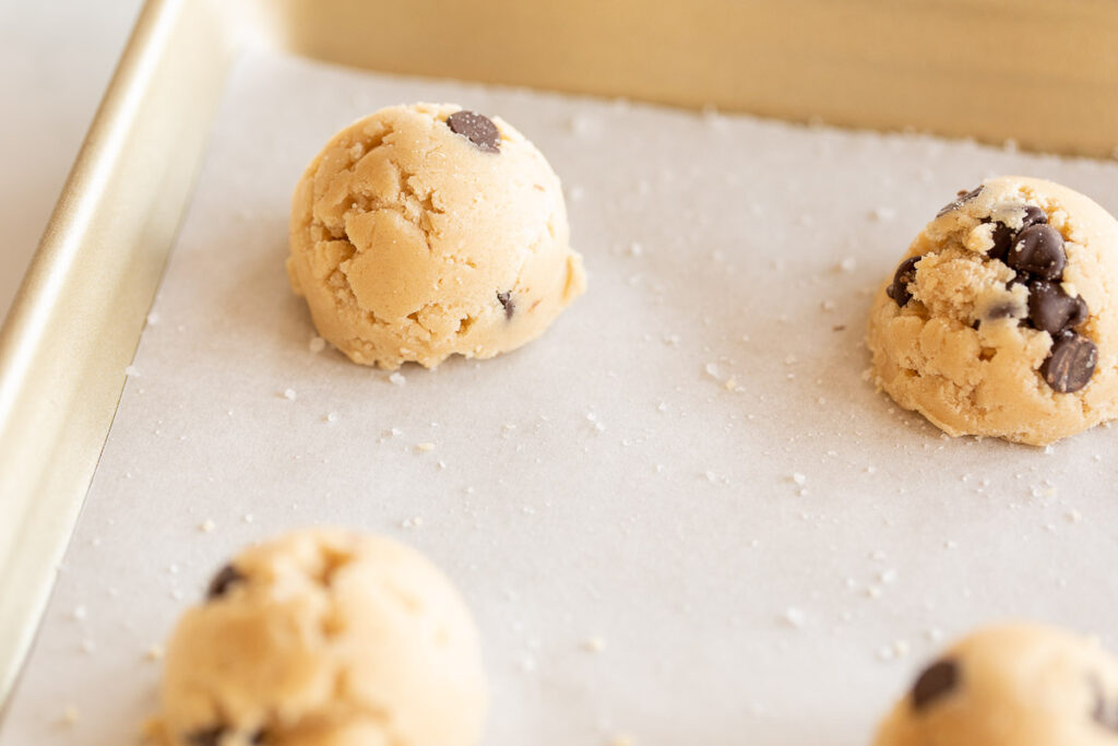 eggless chocolate chip cookie dough balls on parchment lined baking sheet