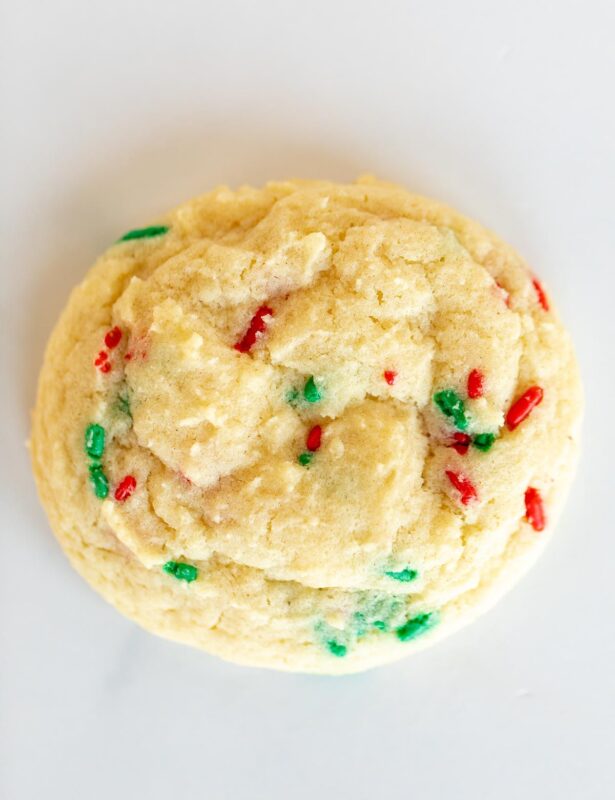 A single homemade Christmas funfetti cookie on a white surface.