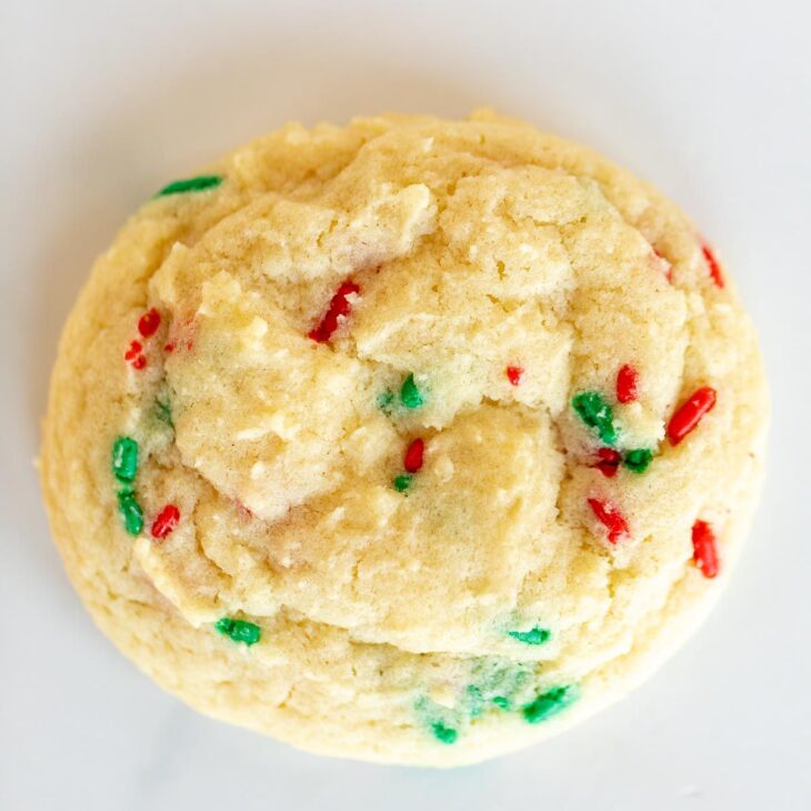 A single homemade Christmas funfetti cookie on a white surface.