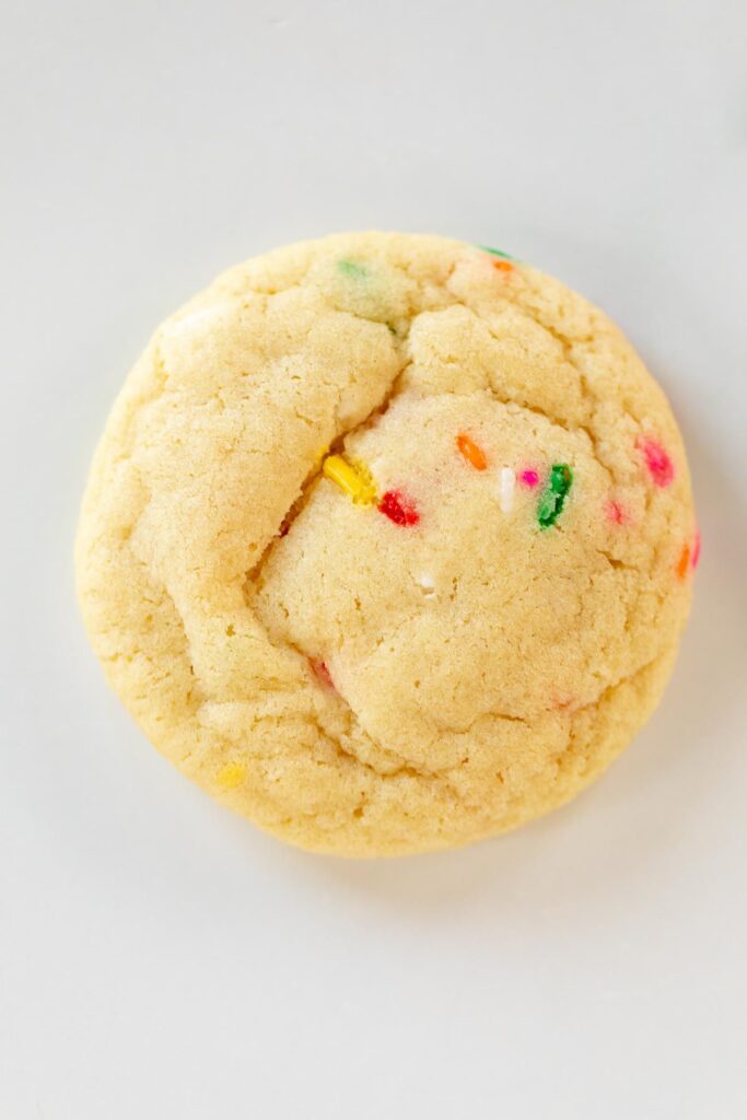 A single baked funfetti cookie on a white surface.