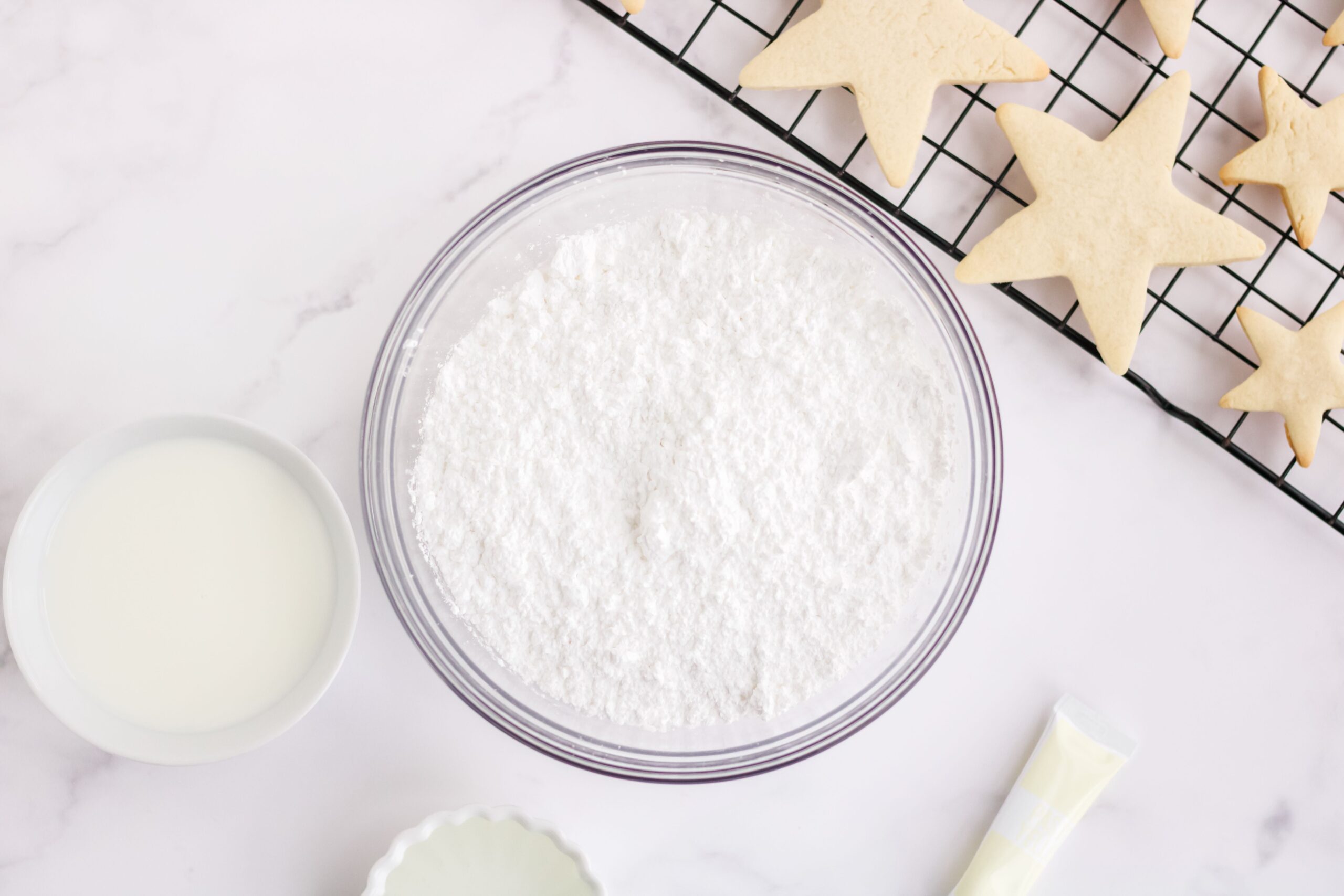 A clear glass bowl of powdered sugar for a sugar cookie icing recipe.
