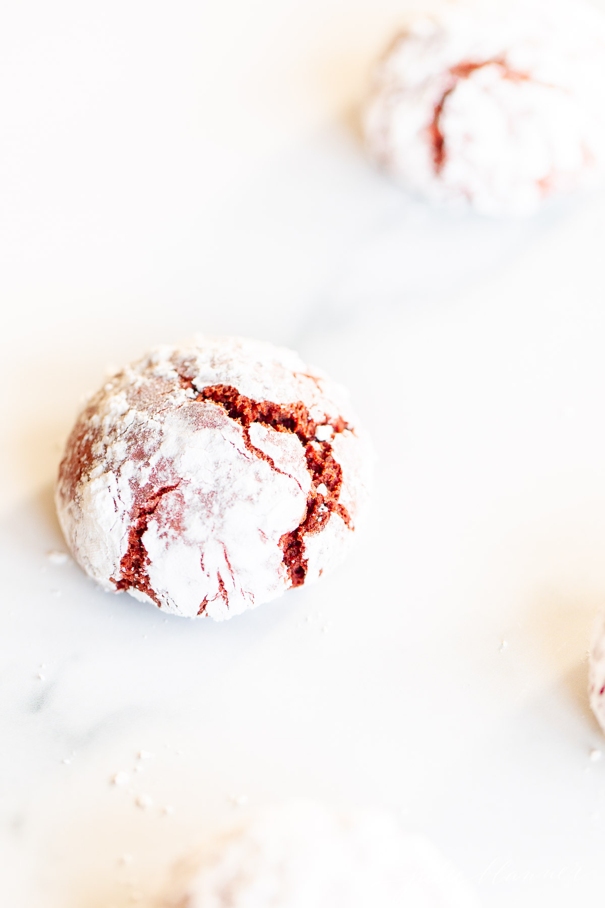 red velvet cookies covered in powdered sugar on marble surface