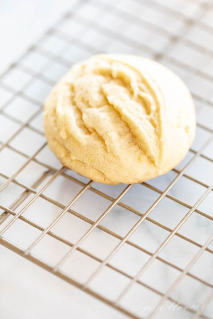 Small lemon cookie on a wire cooling rack on a marble countertop.