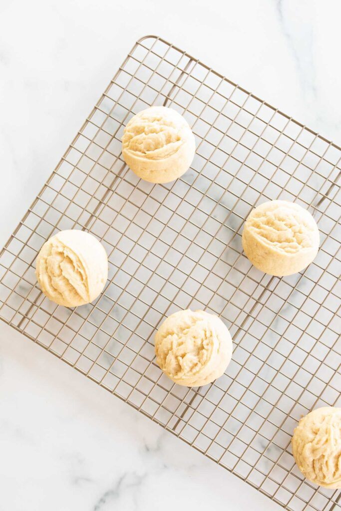 Small lemon cookies on a wire cooling rack on a marble countertop.