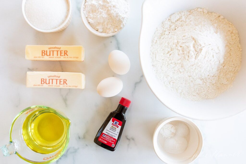 Ingredients for lemon cookies laid out on a marble surface.