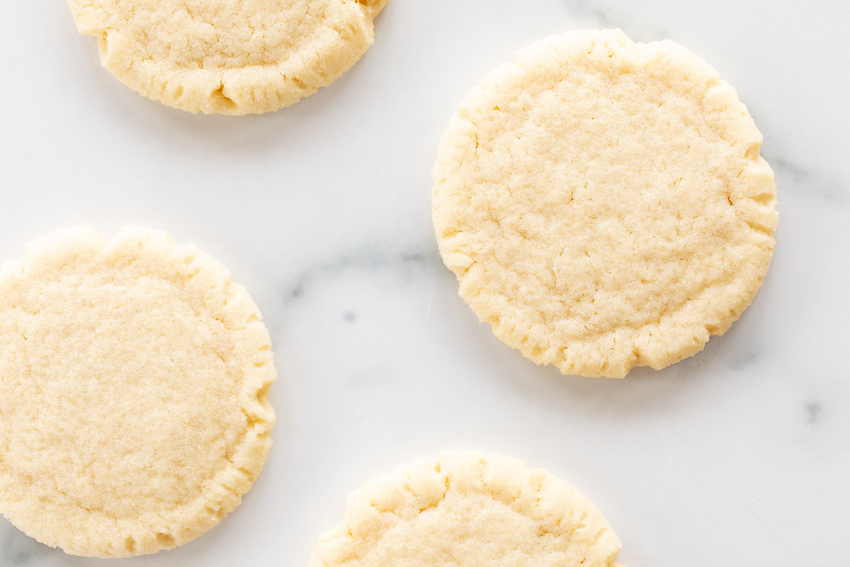 sugar cookies pressed with a glass scattered on marble counter