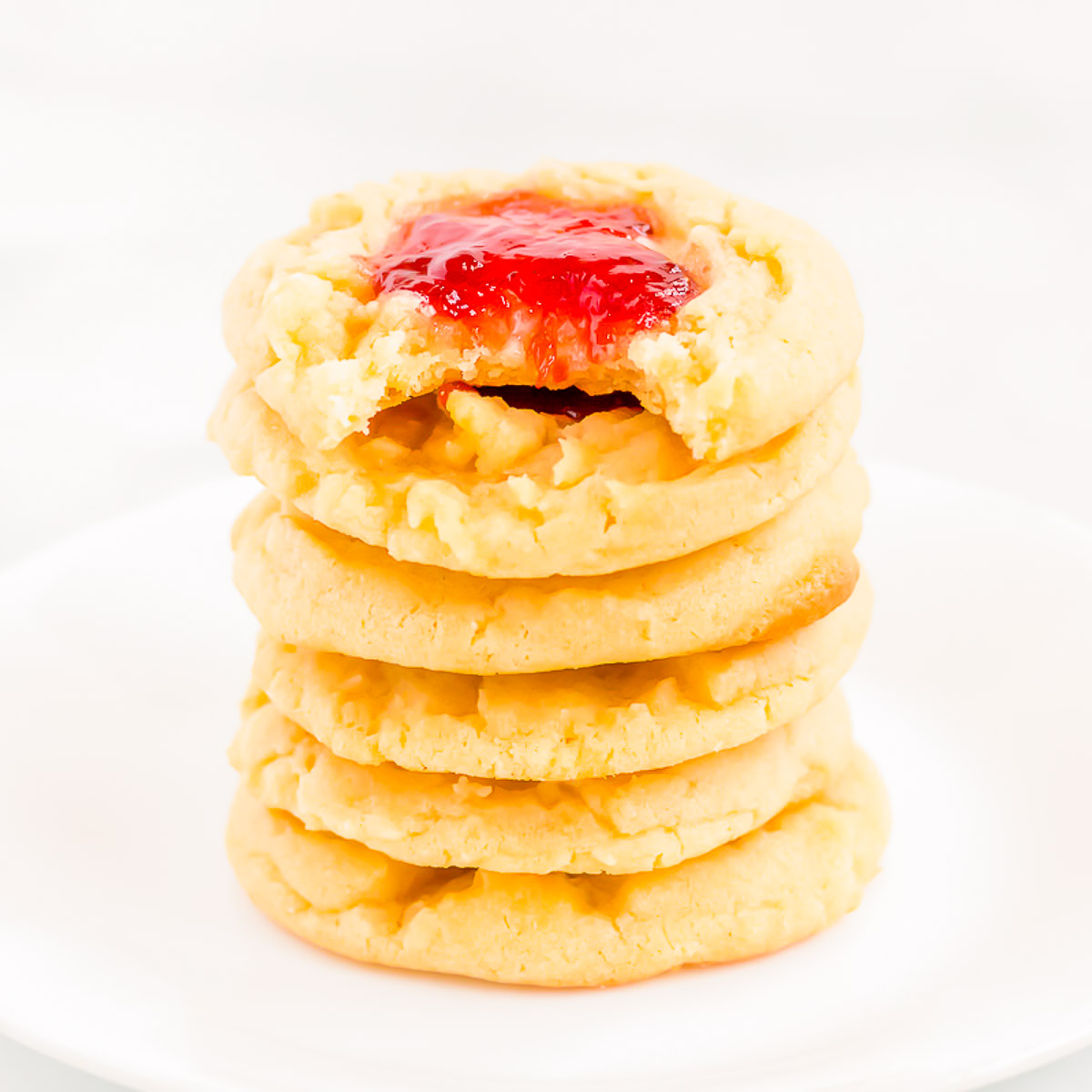 A white plate filled with a stack of strawberry cheesecake cookies.