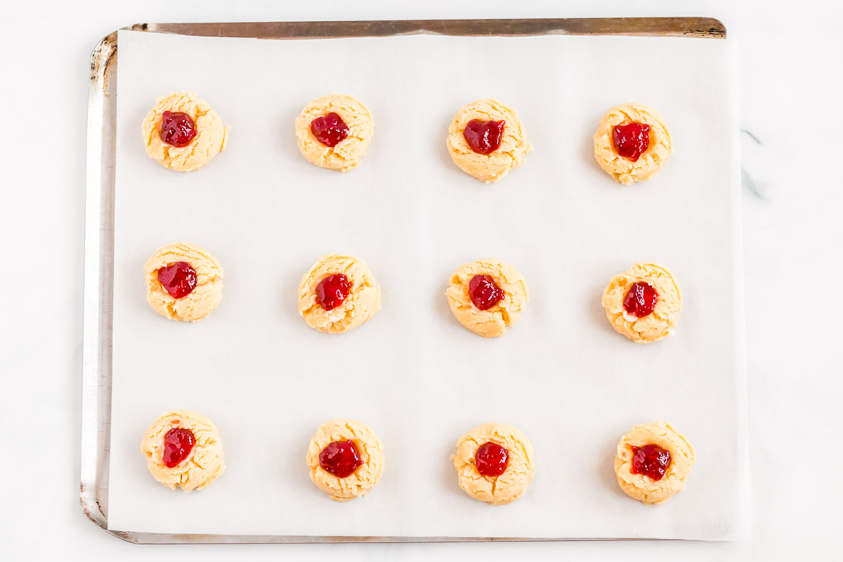 Strawberry cheesecake cookies on a baking sheet lined with parchment paper.