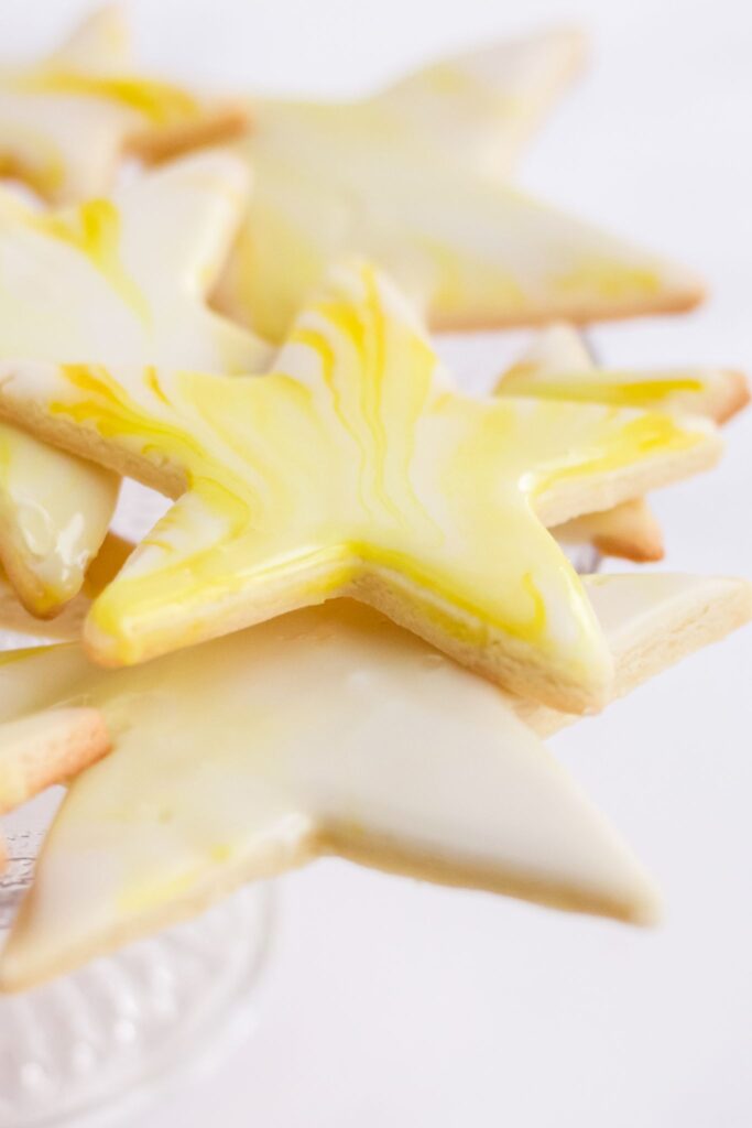 Star shaped cutout sugar cookies topped with yellow marbled royal icing.