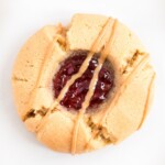 A homemade peanut butter and jelly cookie on a white surface.