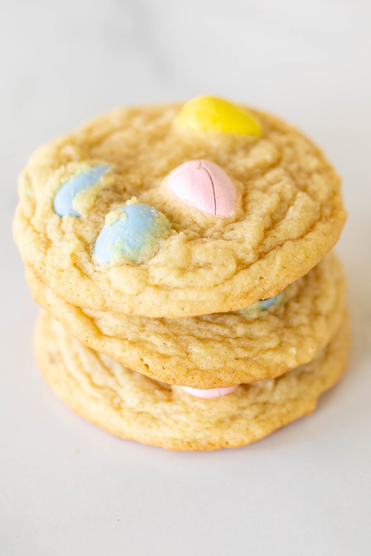 A stack of multiple mini egg cookies, on a marble surface for Easter.
