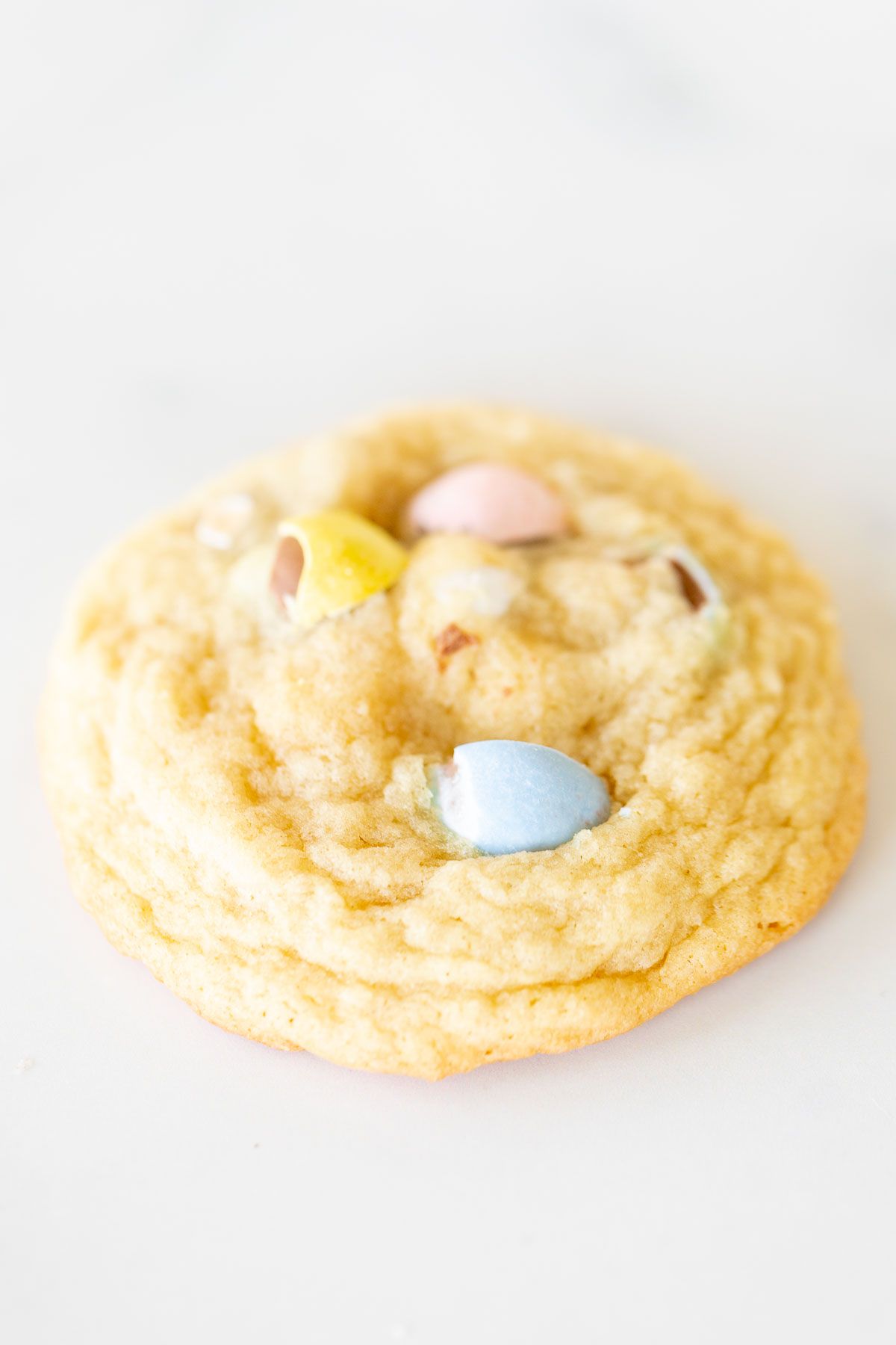 A single Easter cookie with mini cadbury eggs on a marble surface.