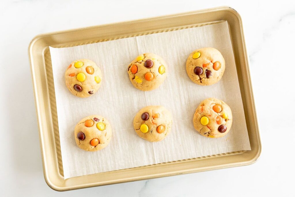 baked reeses pieces cookies on a cookie sheet lined with parchment paper