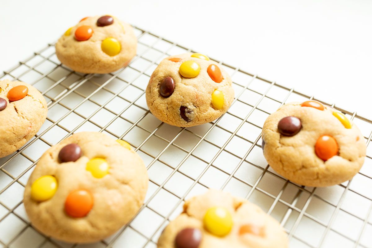 cookies with colorful reeses candies on a wire cooling rack