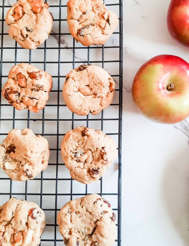 Apple raisin softie cookies on a baking sheet, apples nearby.