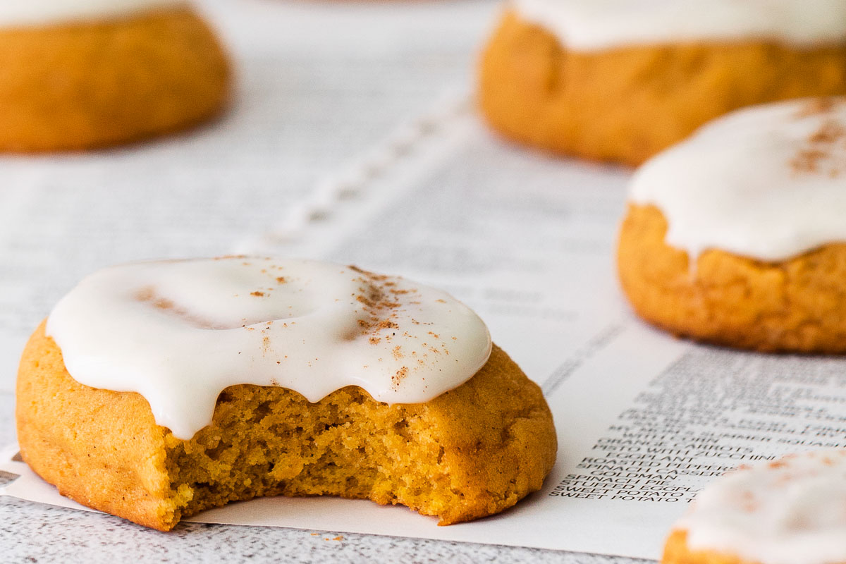 Pumpkin cookies with cream cheese frosting on a white countertop