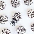 oreo spider cookies laid out on a white surface with a black plastic spider nearby