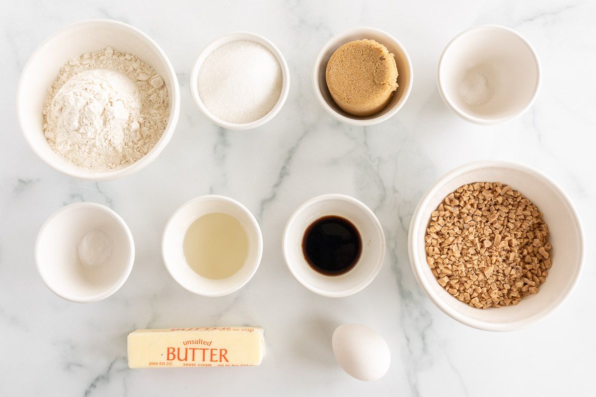 Ingredients for browned butter toffee cookies laid out on a marble countertop.