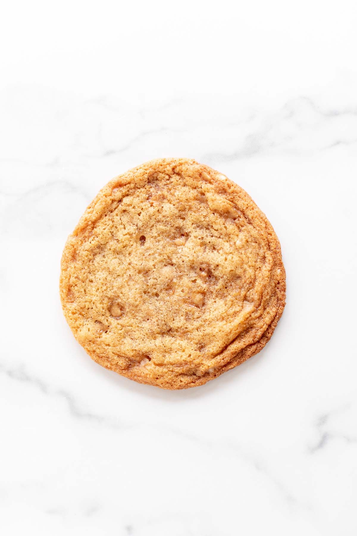 A single brown butter toffee cookie on a white background