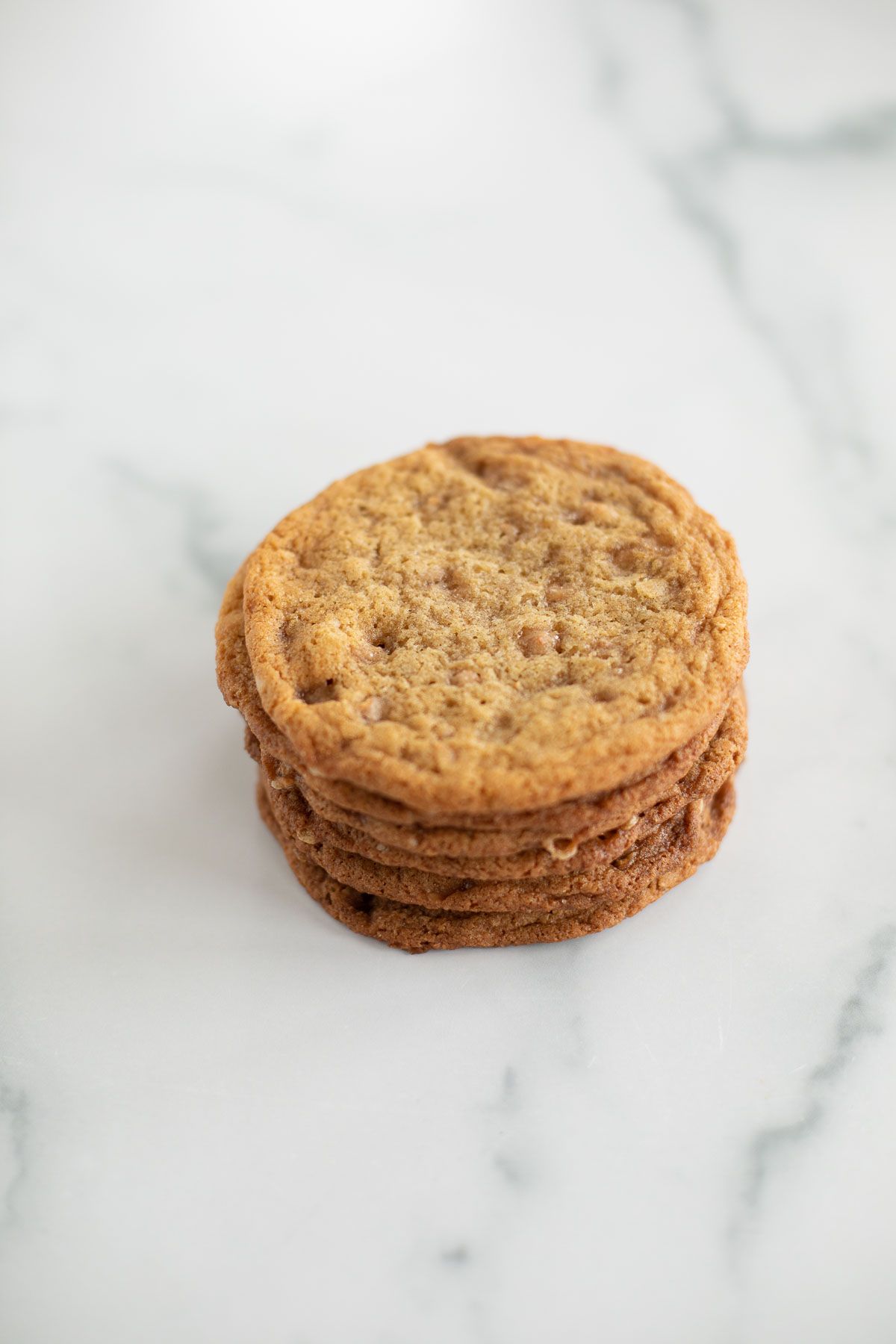 brown butter toffee cookies stacked on a marble surface