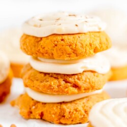Pumpkin cake cookies on white parchment paper, topped with cream cheese frosting