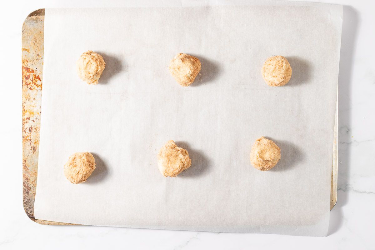 Small balls of cookie dough on a parchment lined baking sheet.