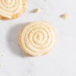 Cinnamon roll cookies swirled with cream cheese icing, on a white countertop.