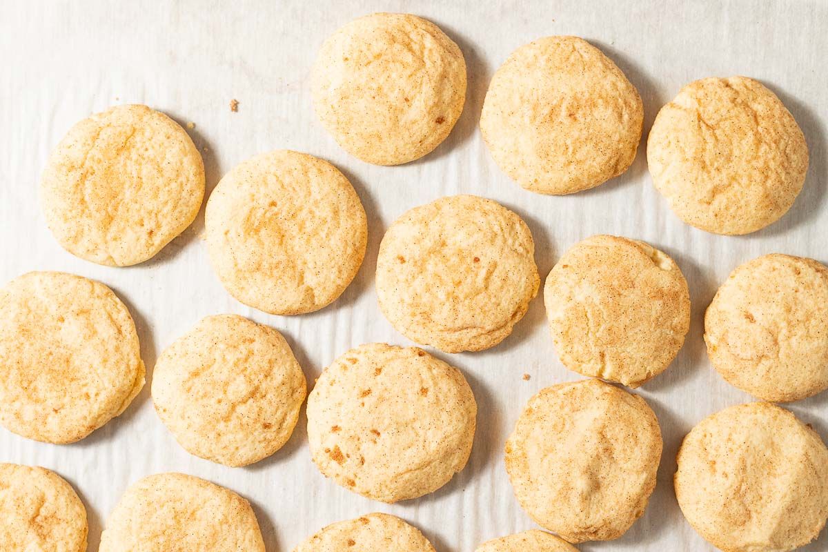 Small cinnamon cookies on a parchment lined baking sheet.