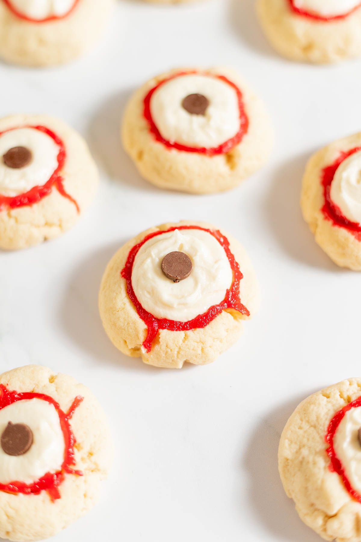 Eyeball cookies with red and white frosting, on a white surface