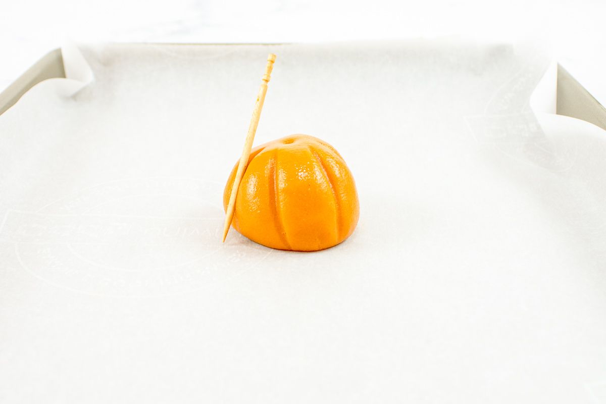 A small orange no bake cookie on a parchment lined baking sheet.