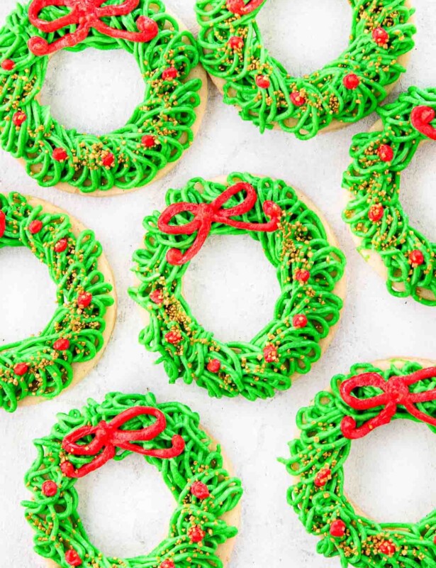 Red and green Christmas wreath cookies laid out on a white countertop.