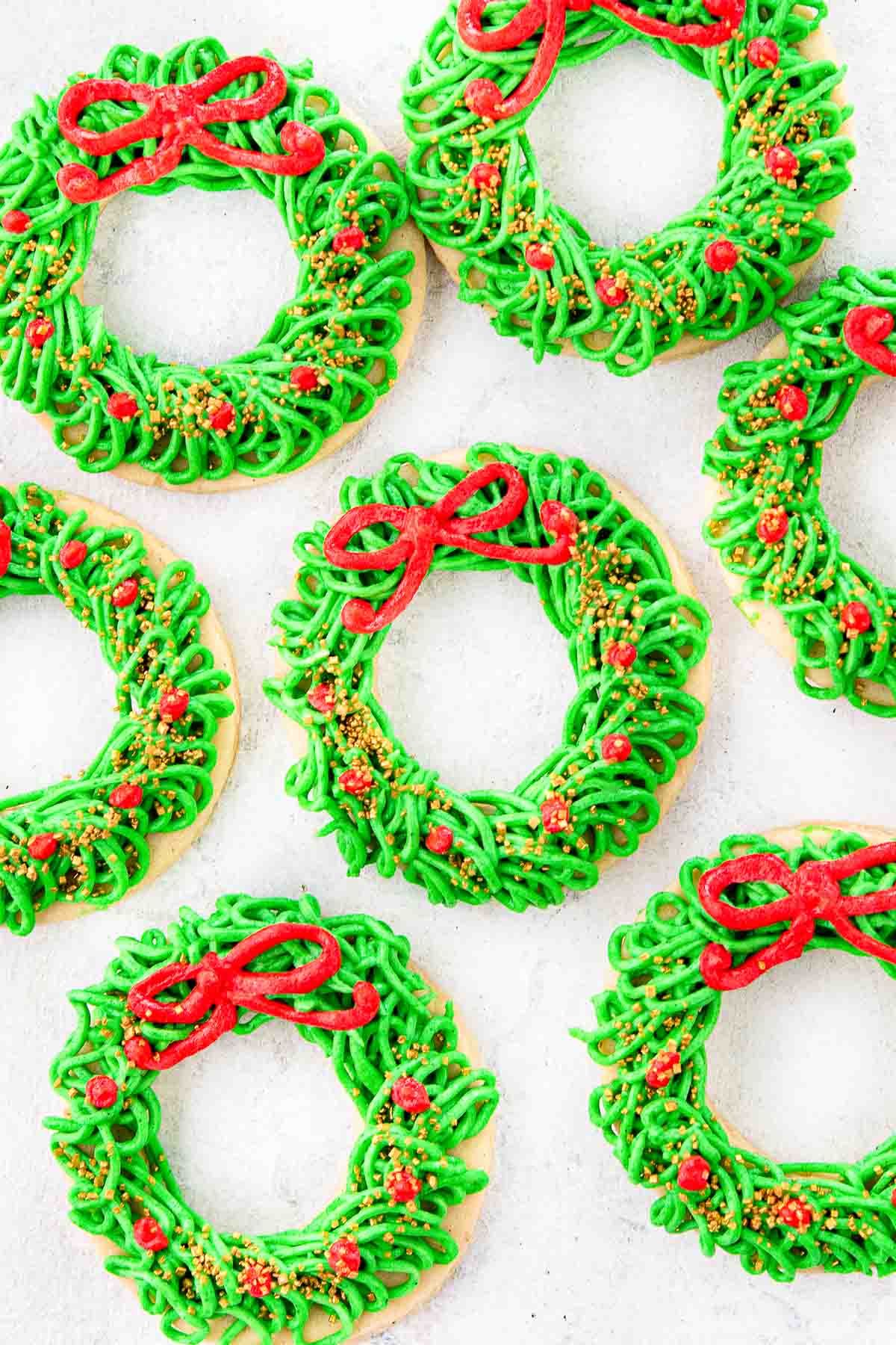 Red and green Christmas wreath cookies laid out on a white countertop. 