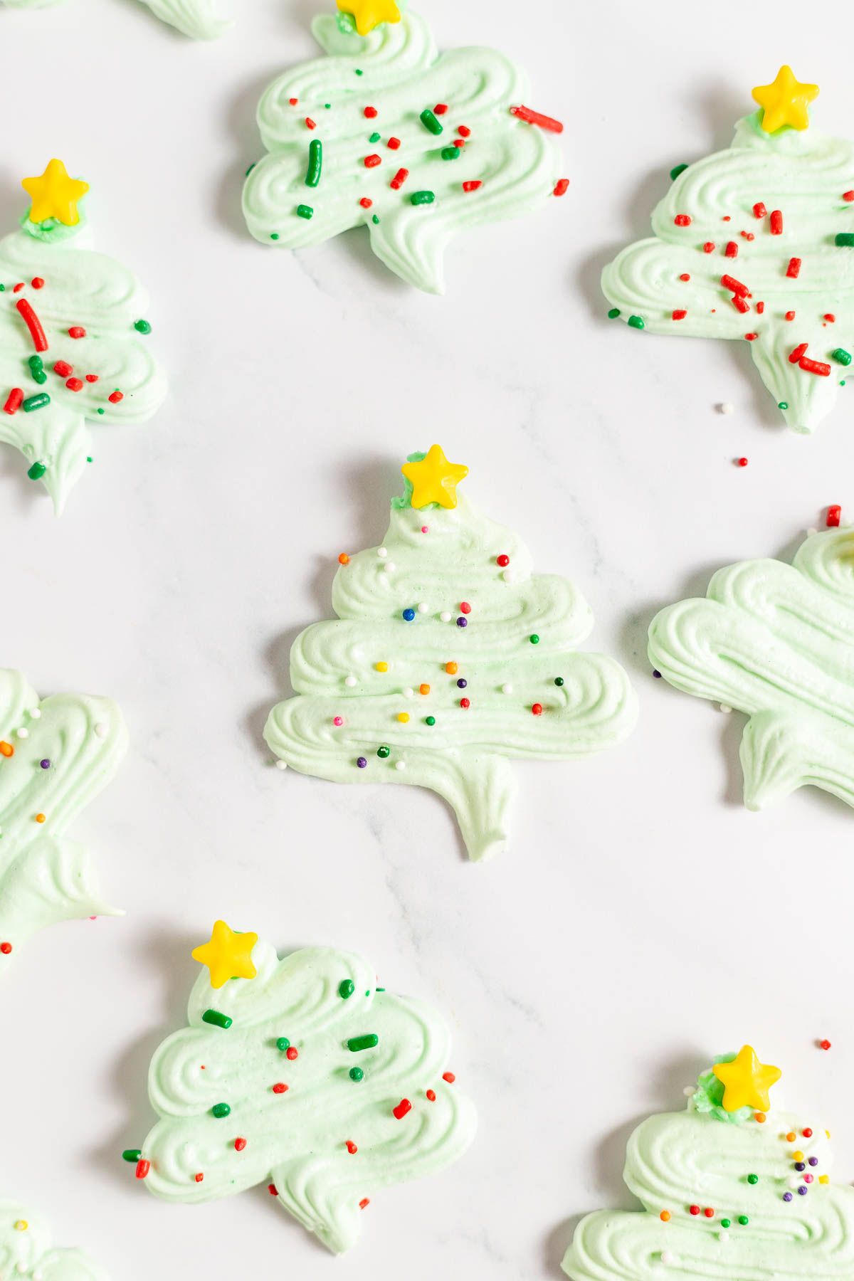 Pale green Christmas tree Meringue cookies against a white surface.