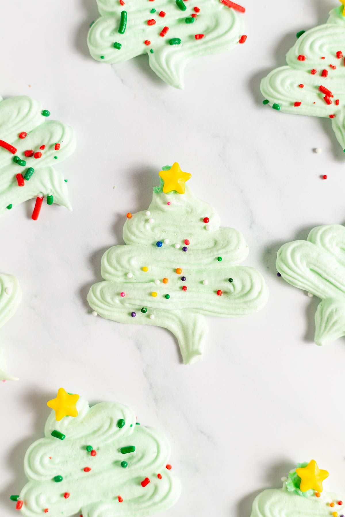 Pale green Christmas tree Meringue cookies against a white surface.