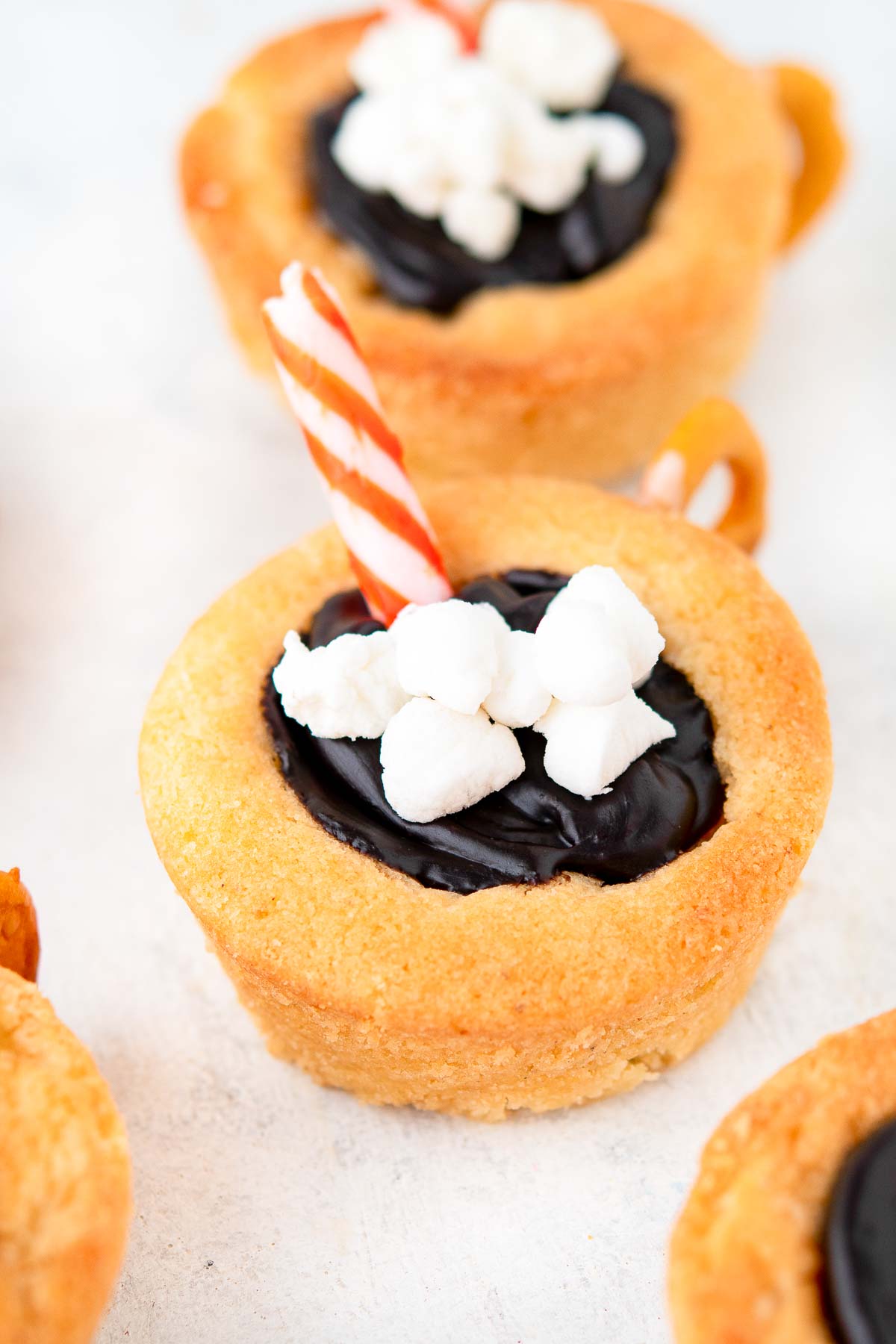 Hot chocolate cookie cups on a white surface.