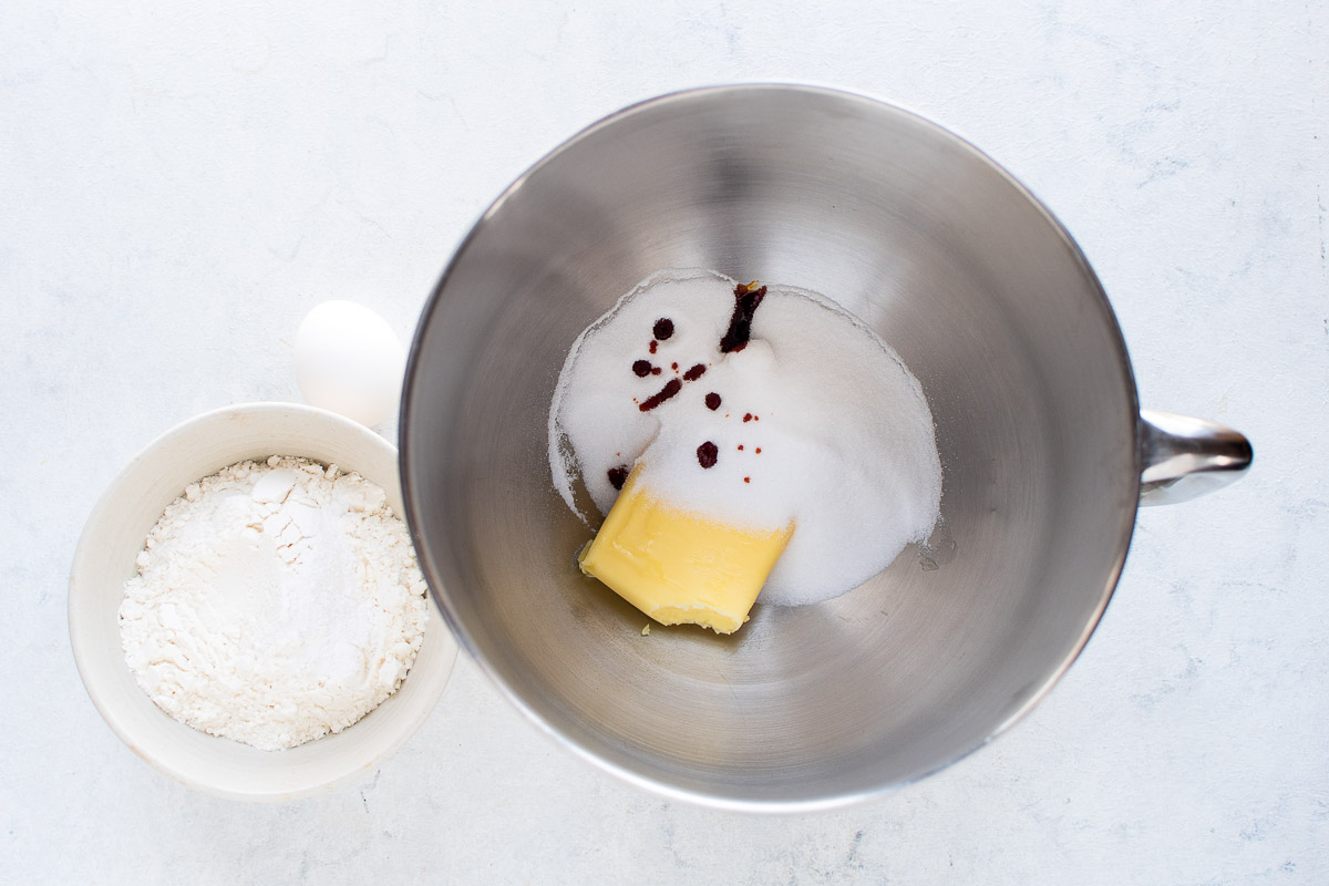 The bowl of a stand mixer filled with ingredients for cookie dough.