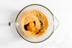 Overhead view of vanilla and egg added to bowl of creamed butter, peanut butter, and sugar