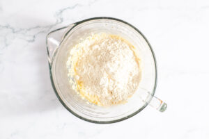 Overhead view of flour added to wet ingredients for Danish butter cookies